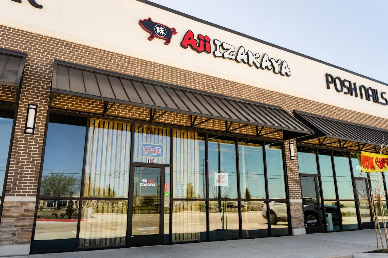 Exterior storefront of Aji Izakaya with branded pig logo and glass entrance at Aji Izakaya Rosenberg, a Japanese Restaurant in Rosenberg